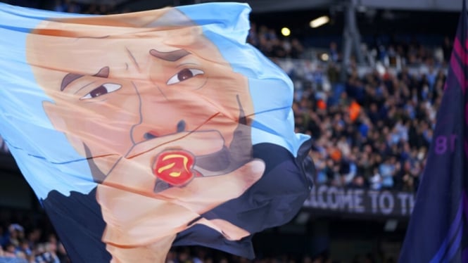 Suporter Manchester City mengibarkan bendera bergambar wajah Pep Guardiola
