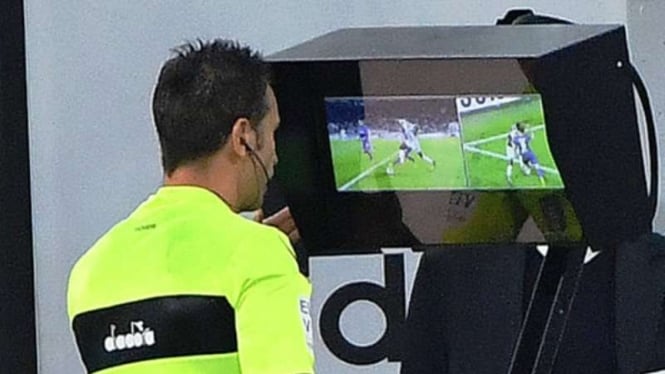 Seorang wasit menggunakan teknologi Video Assistant Referee (VAR)